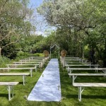 Espace de cérémonie de mariage avec des bancs et une allée en tissu blanc